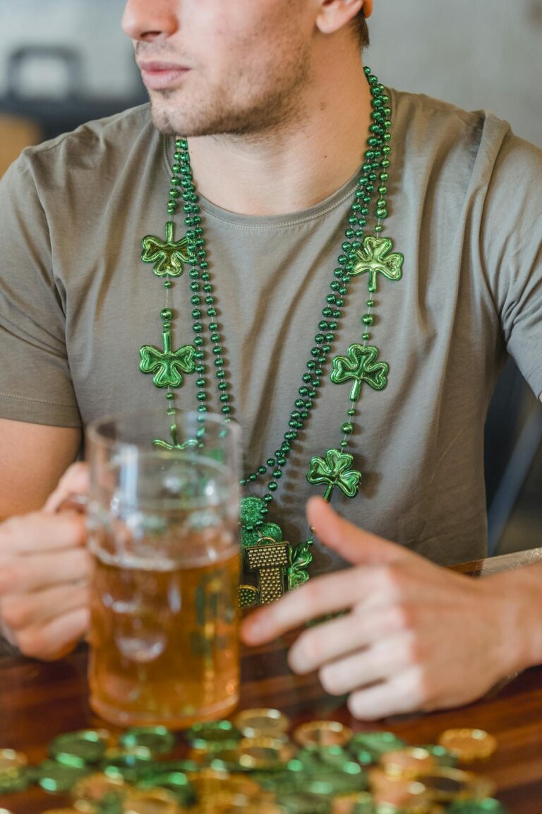Man wearing shamrock necklace holding a beer during St. Patrick's Day celebration.